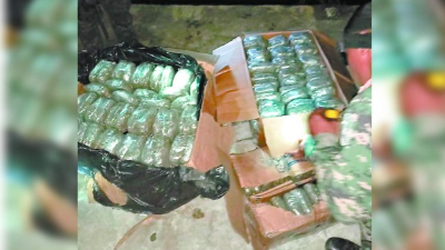 Un agente militar inspecciona las tres cajas en las que venía la marihuana.