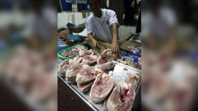 Un carnicero en un mercado de San Pedro Sula corta piezas de pollo para la venta.