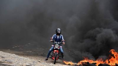 Una motocicleta escapa de una columna de humo en Tegucigalpa.