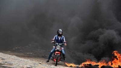 Una motocicleta escapa de una columna de humo en Tegucigalpa.