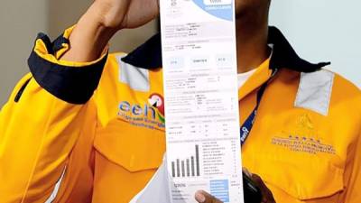 Un empleado de la EEH muestra una factura de consumo eléctrico de un hogar. Archivo