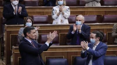 El primer ministro de España, Pedro Sánchez (izquierda, abajo), reconoce el aplauso del viceprimer ministro de Derechos Sociales y Desarrollo Sostenible de España, Pablo Iglesias, y otros diputados durante una sesión del parlamento en Madrid. Foto AFP