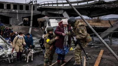 Soldados ucranianos ayudan a una anciana a cruzar un puente destruido mientras evacua la ciudad de Irpin, al noroeste de Kiev.