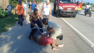 Elementos del Cuerpo de Bomberos junto a ciudadanos brindan asistencia a la mujer que resultó herida.