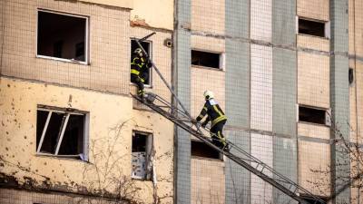 Los bomberos realizan operaciones en un edificio que fue alcanzado por los escombros de un cohete derribado.
