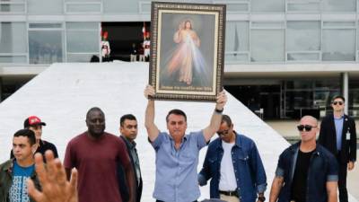 El presidente brasileño, Jair Bolsonaro, plantea una imagen de Jesucristo frente a varias personas. Foto: AFP