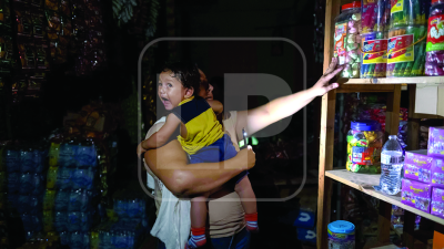 Una madre busca con la luz del teléfono celular alimentos para su hijo en una pulpería localizada en la calle principal del cayo Bonacca, cabecera municipal de Guanaja. Fotos: Yoseph Amaya