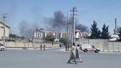 Los hombres afganos caminan por una carretera mientras el humo se eleva desde el lugar de un ataque en Kabul. Foto: AFP