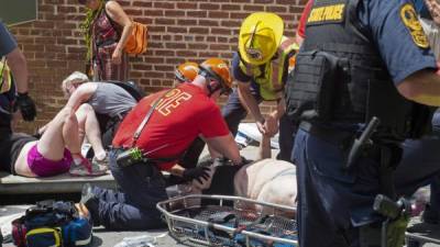 TOPSHOT - Injured people receive first-aid after a car accident ran into a crowd of protesters in Charlottesville, VA on August 12, 2017. A vehicle plowed into a crowd of people Saturday at a Virginia rally where violence erupted between white nationalist demonstrators and counter-protesters, witnesses said, causing an unclear number of injuries. / AFP PHOTO / PAUL J. RICHARDS