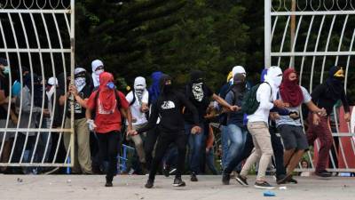 Estudiantes de la Universidad Nacional Autónoma de Honduras (UNAH) se enfrentan con la policía antidisturbios durante una protesta contra la reelección del presidente Juan Orlando Hernández.