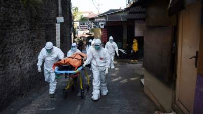Trabajadores de la salud retiraron el cuerpo de una víctima de covid-19 que murió mientras estaba aislada en su casa en Indonesia. Foto AFP