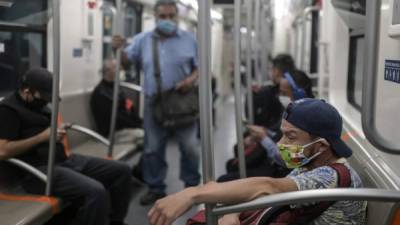 Los viajeros usan mascarillas como medida preventiva contra la propagación del nuevo coronavirus mientras viajan en el metro en la Ciudad de México. Foto AFP