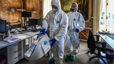 Los empleados de la compañía Italia Opere rocían peróxido de hidrógeno para desinfectar oficinas. Foto AFP