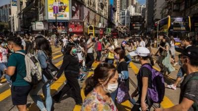 Las personas que usan mascarillas como medida preventiva contra el coronavirus, cruzan una calle en un distrito comercial. Foto AFP