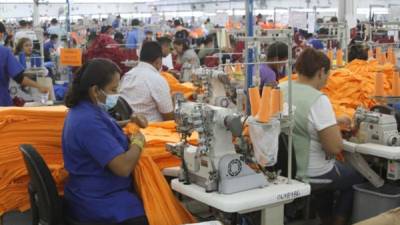Operarios de una maquila textil mientras costuran varias piezas de ropa. Foto archivo.