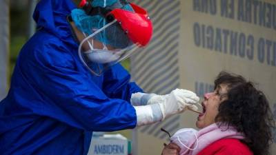 Un trabajador de salud estatal recolecta una muestra de hisopo de una mujer para realizar una prueba de COVID-19. CLAUDIO CRUZ / AFP