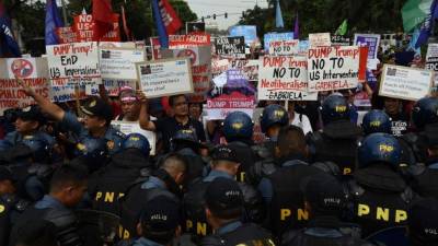 Policías anti distrurbios controlan la manifestación frente a la embajada de EUA en Manila.