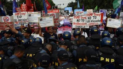 Policías anti distrurbios controlan la manifestación frente a la embajada de EUA en Manila.