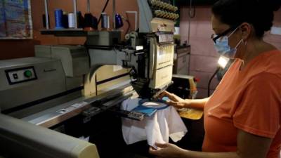 Una mujer opera una máquina para hacer bordados, el 30 de julio de 2021 en un taller en San Salvador (El Salvador).