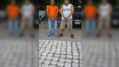 Los sospechosos cuando fueron presentados con la droga que se les decomisó.