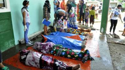 Three unidentified bodies are covered with cloth at the site of an explosion at Barangay Maganda on the outskirts of Lamitan city on the southern island of Mindanao on July 31, 2018.Ten people, including troops and civilians, were killed when an explosion tore through a van at an army checkpoint in the southern Philippines on July 31, as authorities warned the blast could be linked to a wider plot by Islamic militants. / AFP PHOTO / -