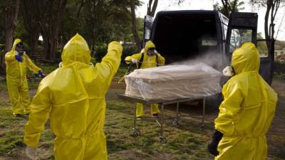 Los trabajadores del cementerio de Campo Santo en la ciudad norteña de Piura, Perú, desinfectan el ataúd de una víctima de COVID-19. Foto AFP