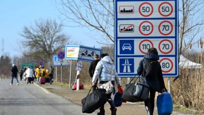 Se ve a familias ucranianas que huyen del conflicto en su país caminando con su equipaje después de cruzar la frontera húngaro-ucraniana cerca de Beregsurany.