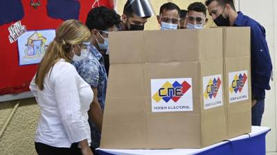 Autoridades y técnicos revisan una máquina de votación en un colegio electoral durante las elecciones regionales y municipales en Fuerte Tiuna en Caracas.