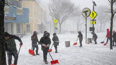 La gente palea fuera de la estación MBTA de Davis Square durante la tormenta de nieve en Somerville, Massachusetts.