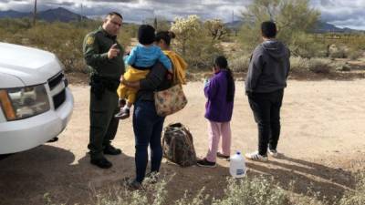 Un miembro de la patrulla fronteriza habla con una hondureña junto a sus tres hijos de 2, 9 y 14 años en un punto del área conocido como Quitobaquito, en la frontera de Arizona con México. EFE