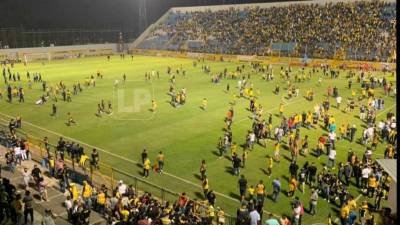 Aficionados ingresaron al césped del estadio Morazán para tratar de protegerse.