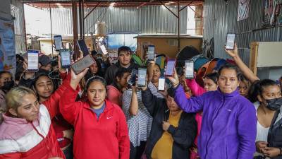 Migrantes que residen en el albergue Movimiento Juventud 2000 muestran en su celular las fallas de la aplicación CBP One.