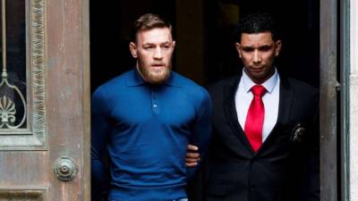Conor McGregor es escoltado mientras abandona, esposado, una comisaria neoyorquina. Foto EFE