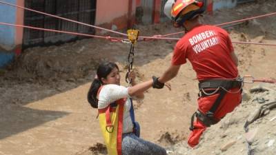 Un bombero voluntario rescata a una residente del distrito de Huachipa, en el este de Lima, cuyas calles se han convertido en ríos de agua lodosa.