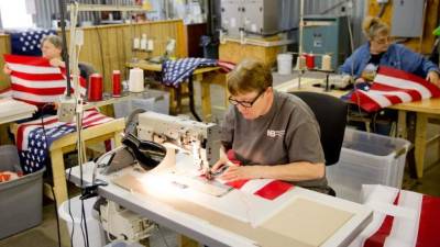 Unos operarios trabajan en una empresa textil de banderas estadounidenses.