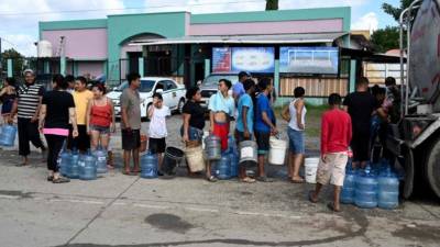 Afectados por la tormenta Eta hacen fila para recolectar agua.