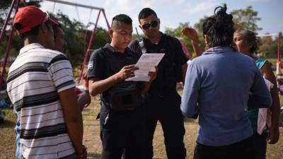 TOPSHOT - Municipal policemen check the documents of Central American migrants taking part in a caravan called 'Migrant Viacrucis' towards the United States as they remain stranded in Matias Romero, Oaxaca State, Mexico, on April 3, 2018. The hundreds of Central Americans in the 'Way of the Cross' migrant caravan have infuriated Trump, but they are not moving very fast -- if at all -- and remain far from the US border. As Trump vowed Tuesday to send troops to secure the southern US border, the caravan was camped out for the third straight day in the town of Matias Romero, in southern Mexico, more than 3,000 kilometers (1,800 miles) from the United States. / AFP PHOTO / VICTORIA RAZO