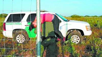 Momento en que la migrante hondureña es llevada a la patrulla por un agente para trasladarla a un hospital.