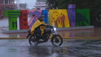 Un hombre protegido con capa maneja su moto en medio de un fuerte aguacero en la población de Tizimin, en el estado de Yucatán (México).