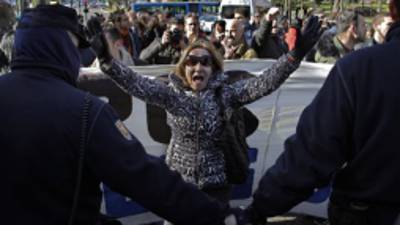 Police stand guard as a demonstrator shouts slogans to executives, unseen, as they walk past during a protest to stop evictions and against the 'Spain, Investors Day' in front of the Ritz Hotel in Madrid, Spain, Tuesday Jan. 15, 2013. Dozens of members of Mortgage Victims' Platform (PAH), were holding a protest outside a Ritz Hotel against the 'Spain, Investor Day', a global encounter between leading investors and Listed Spanish Companies, including banks who enforce evictions. The government recently created a task force to study how to reduce evictions because of the devastating personal impact of repossessions due to tough Spanish mortgage rules and growing unease among the public on the subject. (AP Photo/Andres Kudacki)