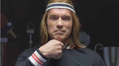 El actor Arnold Schwarzenegger hace rídiculo al jugar tenis de mesa.