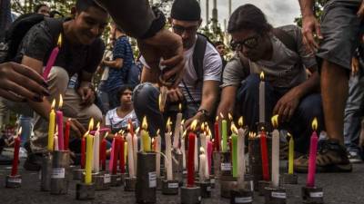 Estudiantes universitarios encienden velas en una plaza pública en Bogotá.