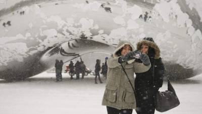 La tormenta de nieve rompió récord en Chicago. Dos turistas se toman una selfie frente a la Cloud Gate.