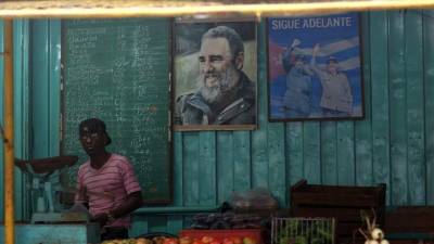 Un hombre vende verduras en un puesto de ventas decorado con imágenes del líder cubano Fidel Castro y de su hermano, el presidente Raúl Castro en una calle de La Habana, Cuba.