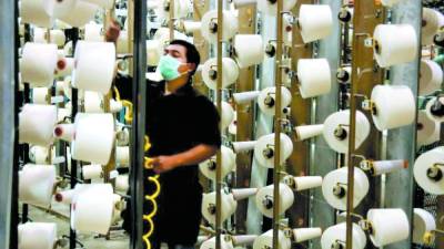 Un trabajador supervisa la producción de hilos en una fábrica de la zona norte del país.