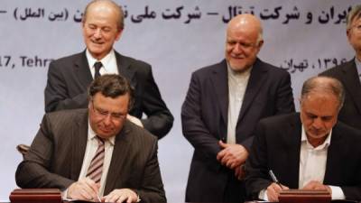 Patrick Pouyanne, presidente ejecutivo de Total (izq.) firma el acuerdo junto a Ezzatolah Akbari, director gerente del Grupo Petropars, en representación del gobierno iraní.