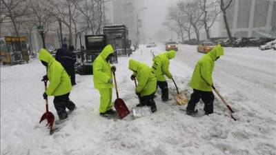 Trabajadores limpian con palas las aceras cercanas al Lincoln Center, durante la primera gran tormenta de invierno en Nueva York (EUA). EFE
