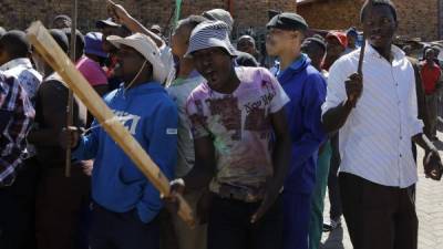 Un grupo de sudafricanos exigiendo a los dueños de un pequeño comercio deJohannesburgo que abandonen el país.