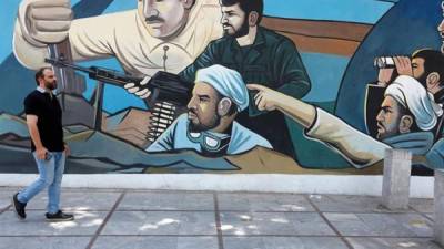Un iraní camina hoy delante de un mural en una calle de Teherán. EFE