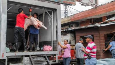 Trabajadores de un puesto de carnicería descargan carne de cerdo en el mercado Medina.